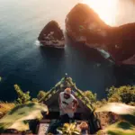 Tourist enjoying the breathtaking hidden viewpoint at Paluang Cliff overlooking the ocean, organized by Nusa Penida Transport Group